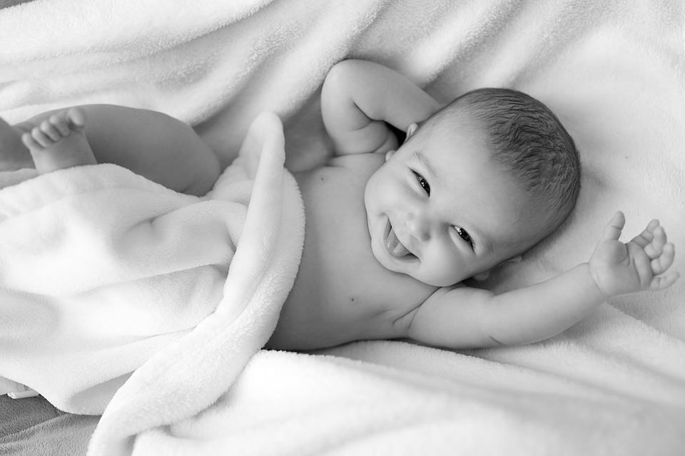 un bambino neonato sorride alla vita con una faccina simpatica. No aborto.