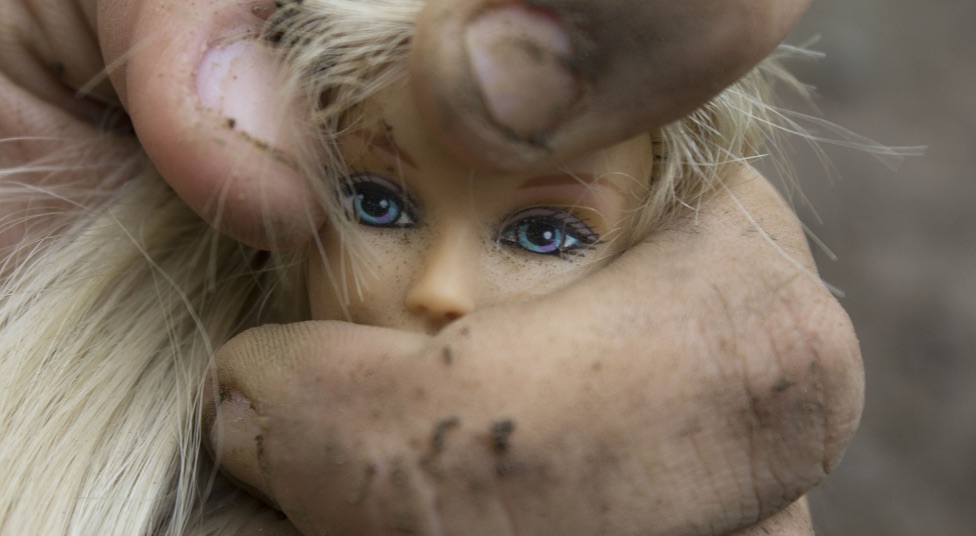 Una mano rude stringe un bambolina: violenza sulle donne, femminicidio