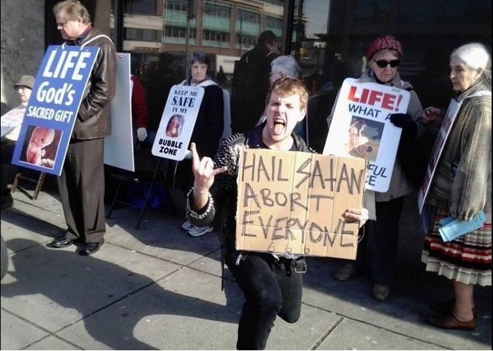 Un satanista con un cartello abortisci tutti disturba una pacifica manifestazione prolife