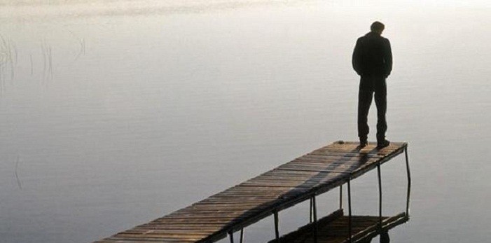 uomo solo su un pontile che guarda l'acqua_ suicidio